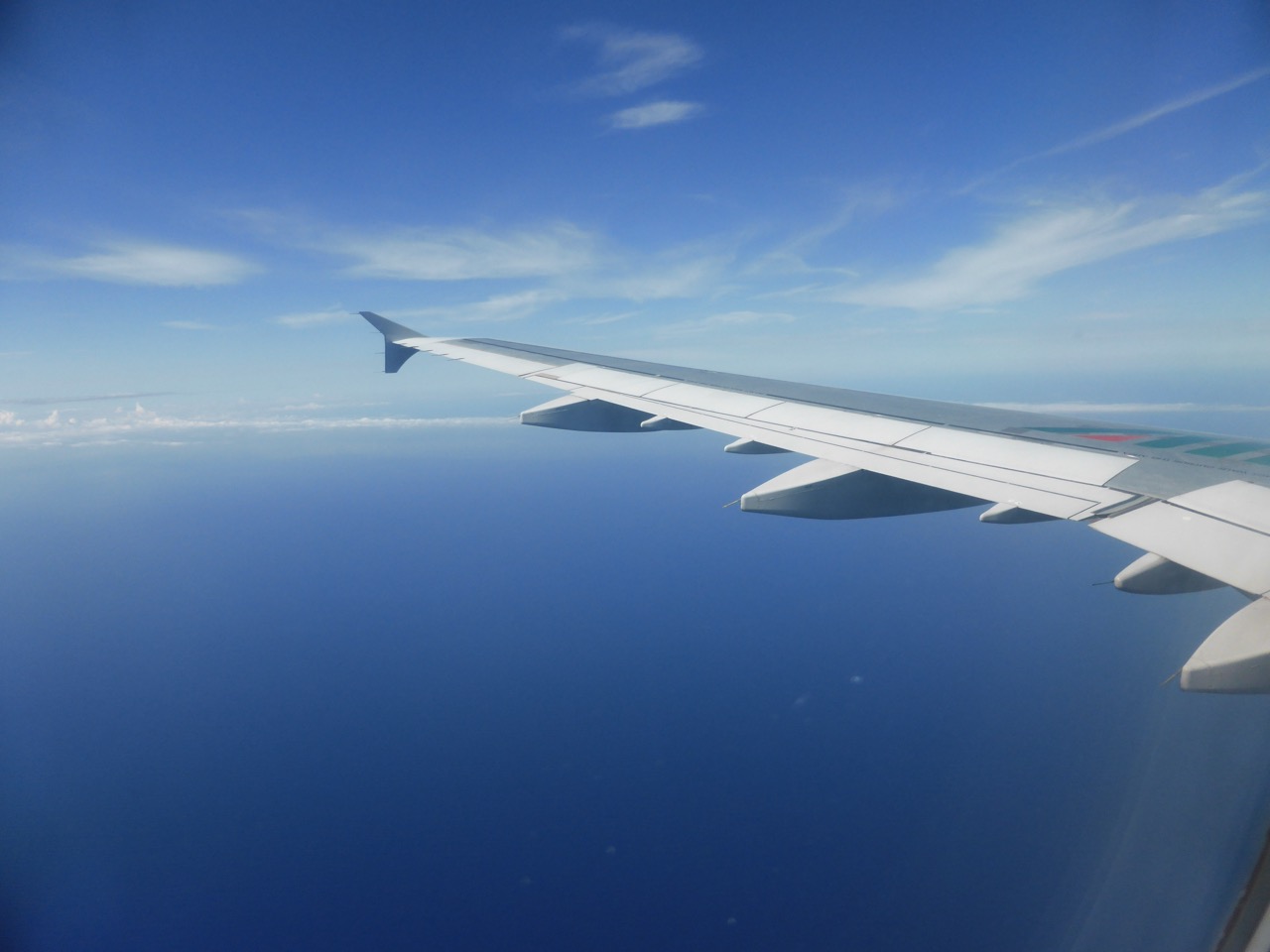 View from an airplane window of a wing over deep blue Mediterranean sea and a bright horizon, the flight to Barcelona