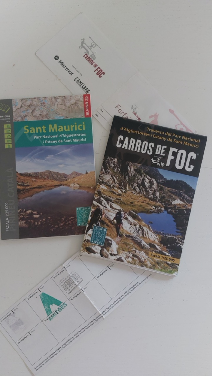 Editorial Alpina 1:25,000 topographic map of Sant Maurici, the Carros de Foc refuge guidebook, and a fold-out stamp card with empty squares for each refuge, laid out on a table
