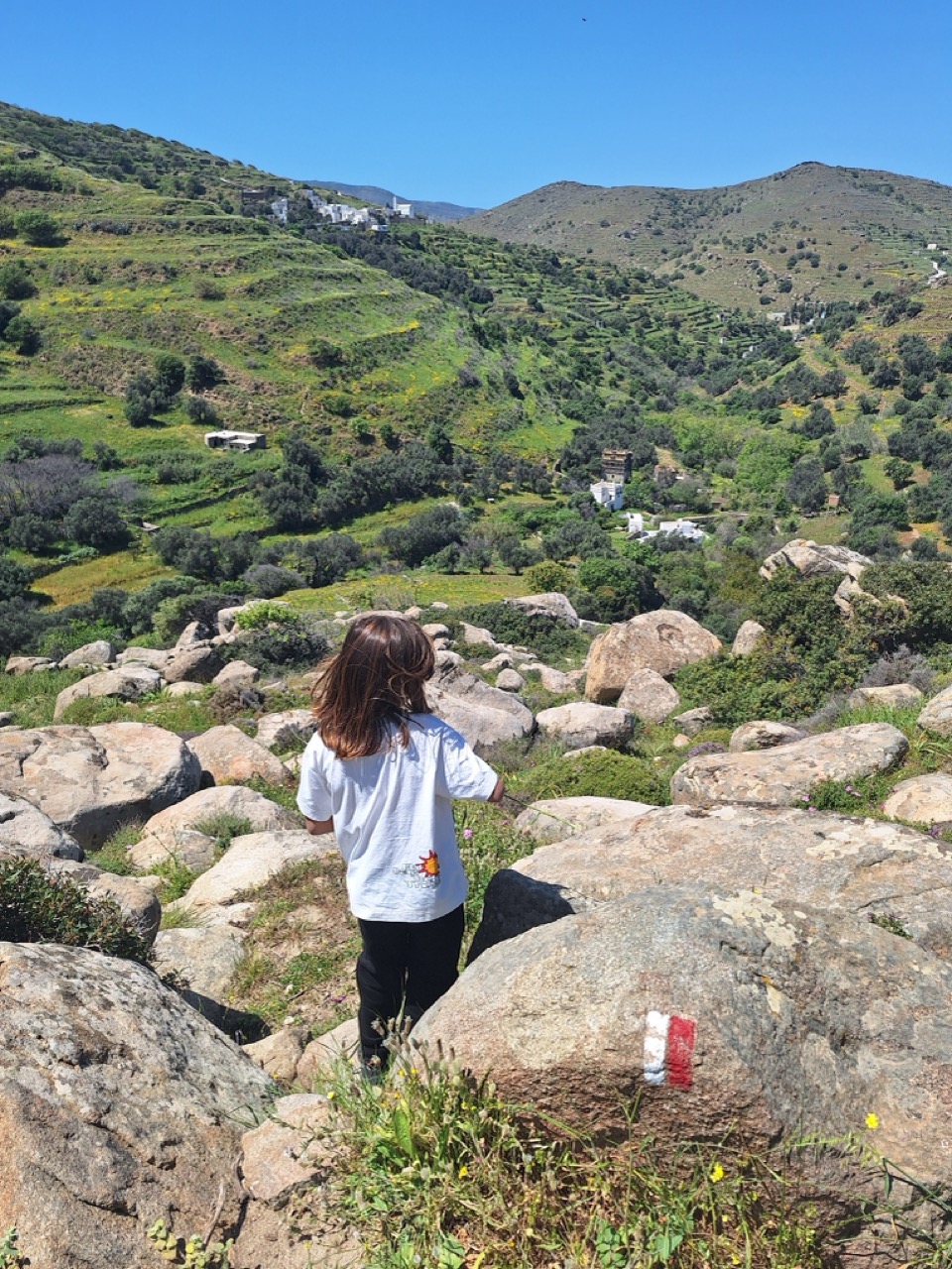 Child among boulders with Tinos valley below