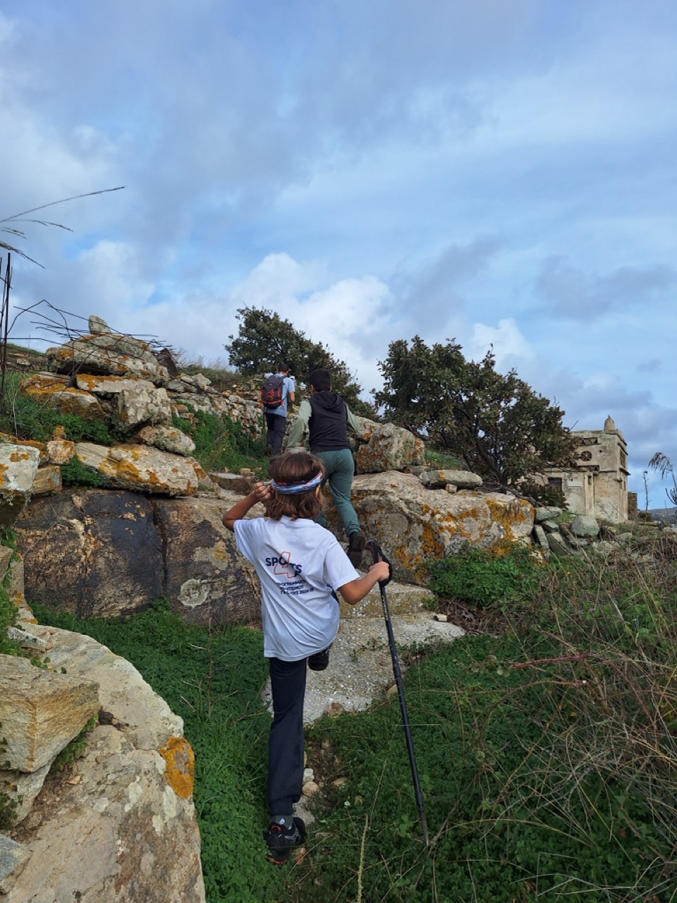 Children climbing a rocky path past an old dovecote