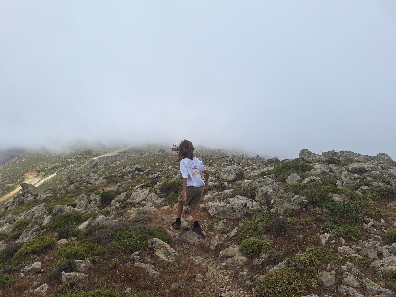 Child on a rocky outcrop with mist rolling in below